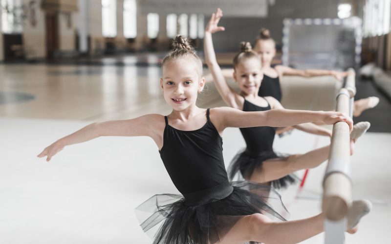 tres-bailarinas-tutu-negro-estirando-sus-piernas-barra