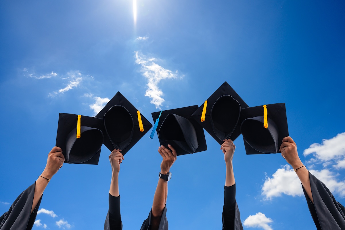 Close up hand of Graduate holding Graduation hats on background of blue sky.
